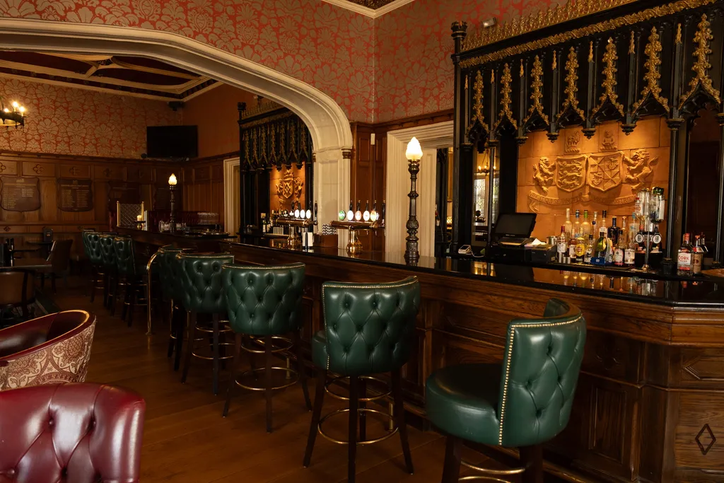 Knights Bar's long bar counter with green leather stools and a carved gothic-style gantry