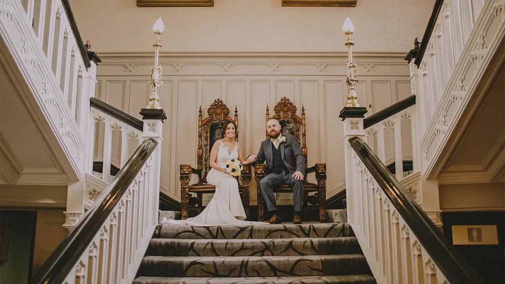 Bride and groom seated on thrones on the castle staircase