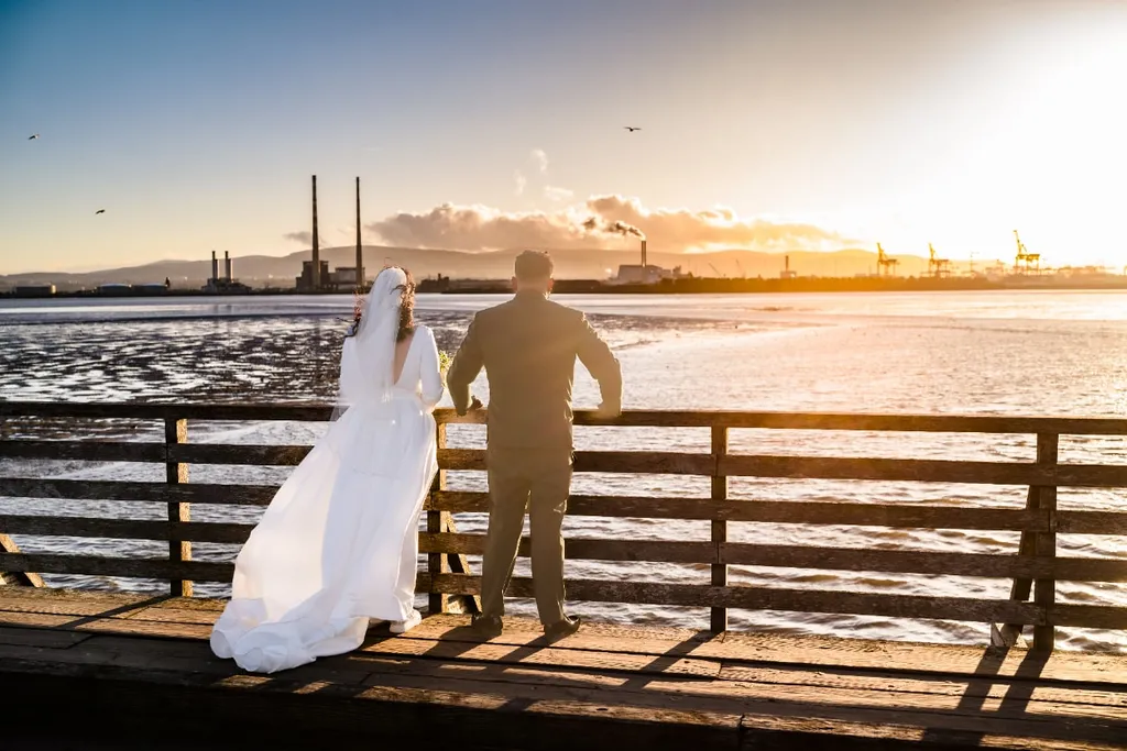 Bride and groom on a wooden pier at sunset