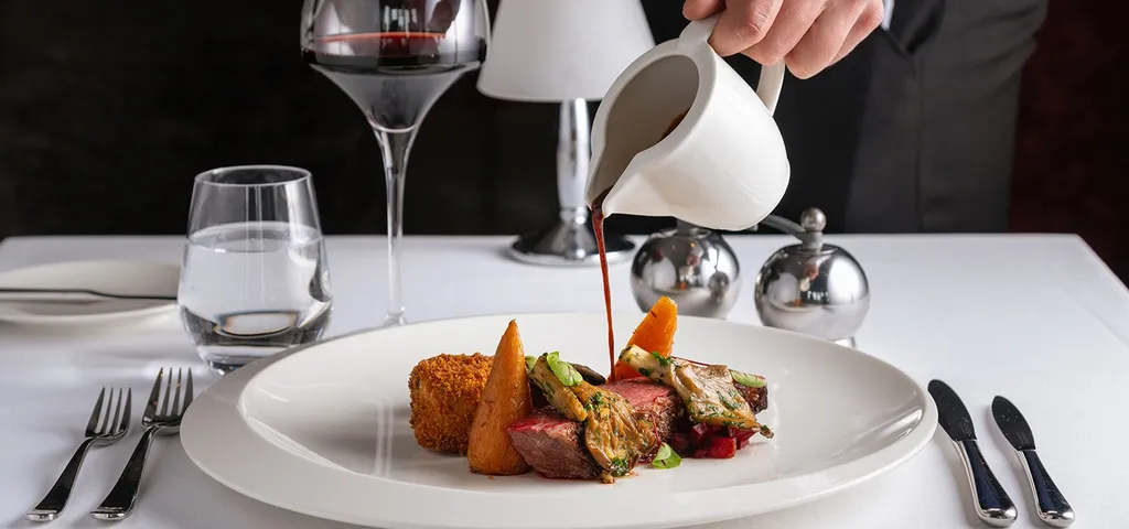 Plated main course with sauce being poured