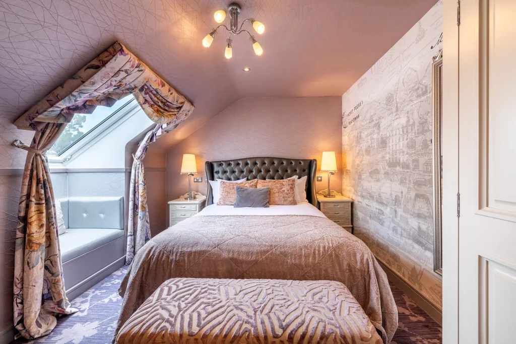Boutique Queen Room in the eaves, with a tufted leather headboard, a window seat beneath the dormer and a toile feature wall