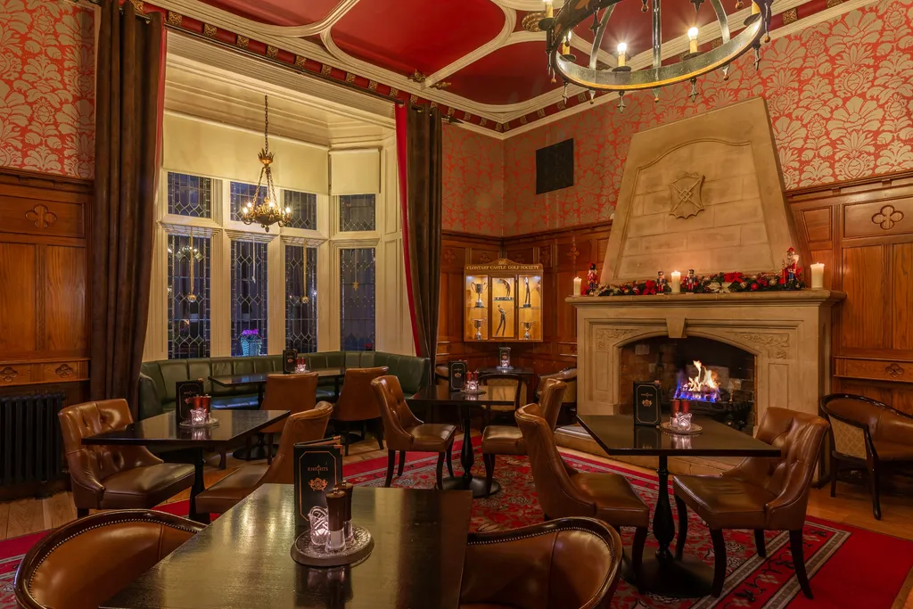 The Knights Bar’s wood-panelled lounge with leather armchairs, red damask walls and a garlanded stone fireplace