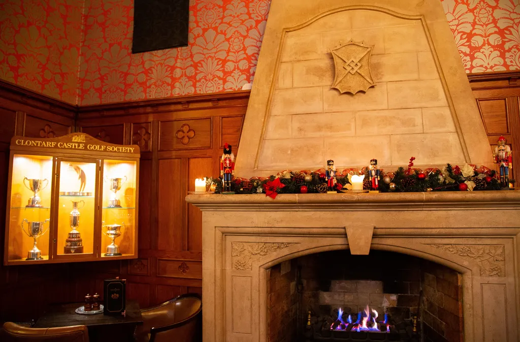 The Knights Bar’s stone fireplace and red damask walls, with nutcrackers on the mantel beside the Clontarf Castle Golf Society trophy cabinet
