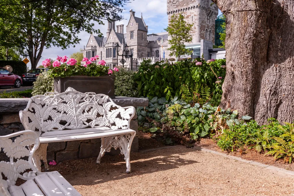 A white garden bench among flowers beneath the castle