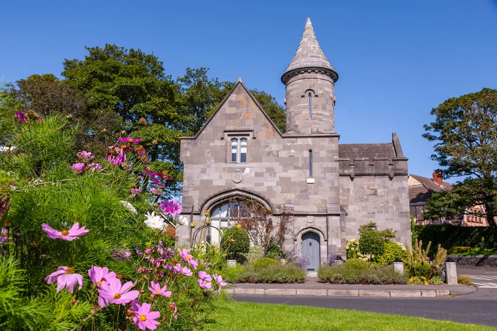 The stone gatehouse beside pink cosmos flowers