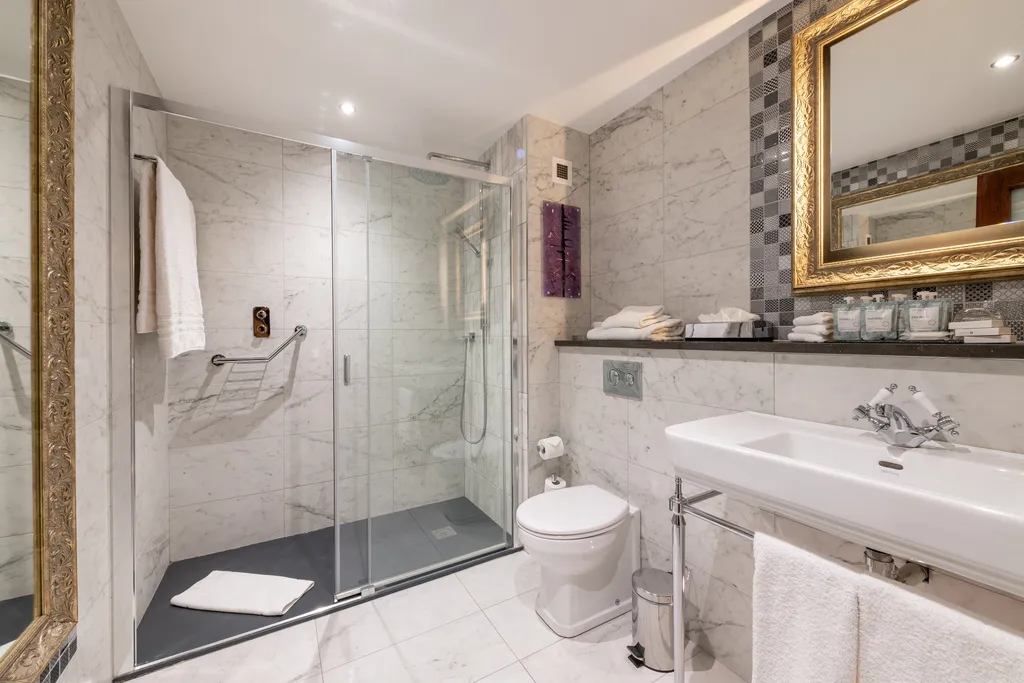 Family Room bathroom with a glass shower, washstand basin and gilt-framed mirror