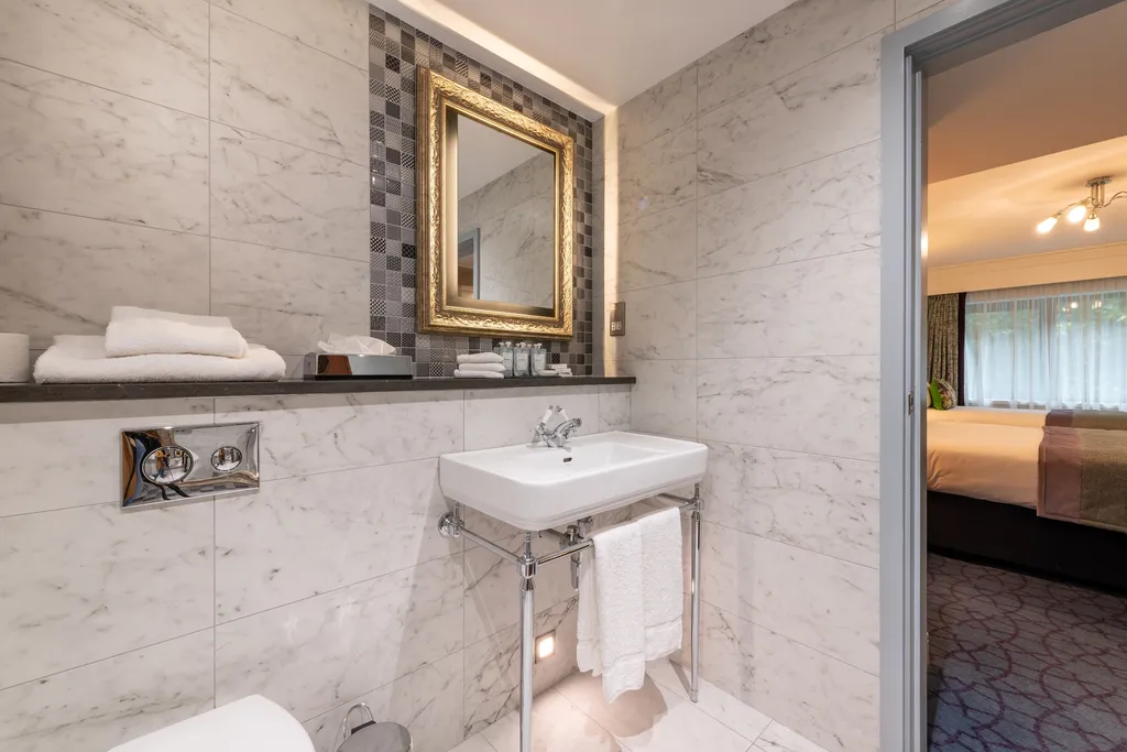 Family Room bathroom with a washstand basin and gilt mirror, the bedroom visible through the door