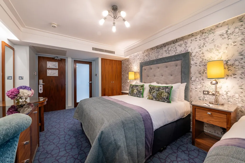 Family Room with a double bed, grey tufted headboard and green cushions, seen from the entrance