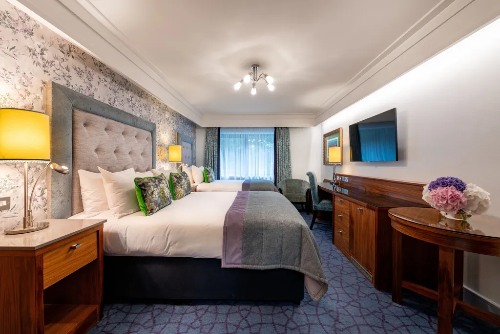 Family Room with two beds, a dresser, wall-mounted TV and window with blue curtains