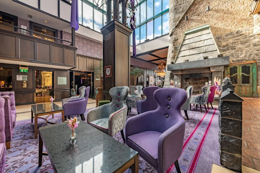 The galleried lobby atrium with lilac armchairs and stone fireplace