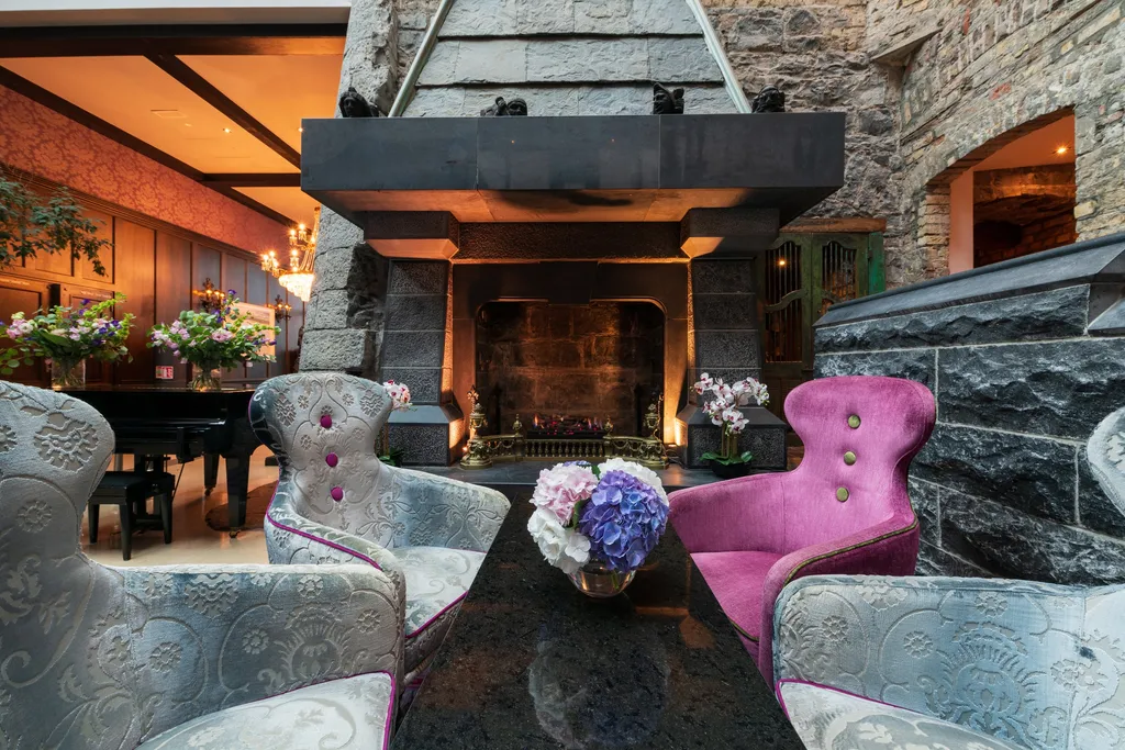 Armchairs around a table of hydrangeas by the lobby fireplace