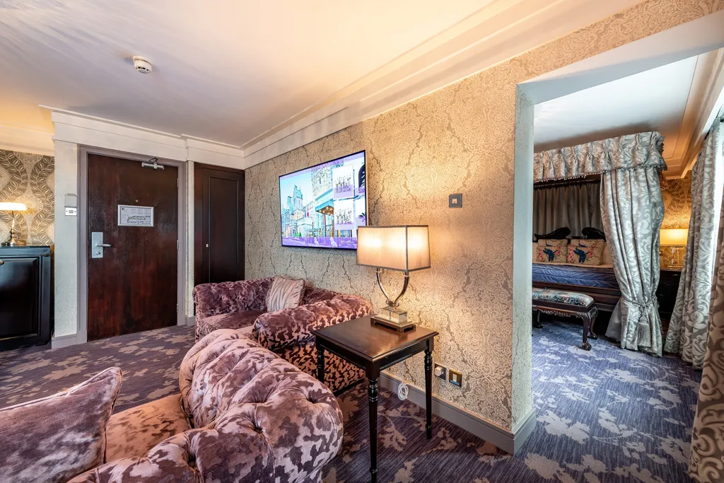 Royal Suite living room with velvet chesterfield sofas and the four-poster bedroom through the doorway