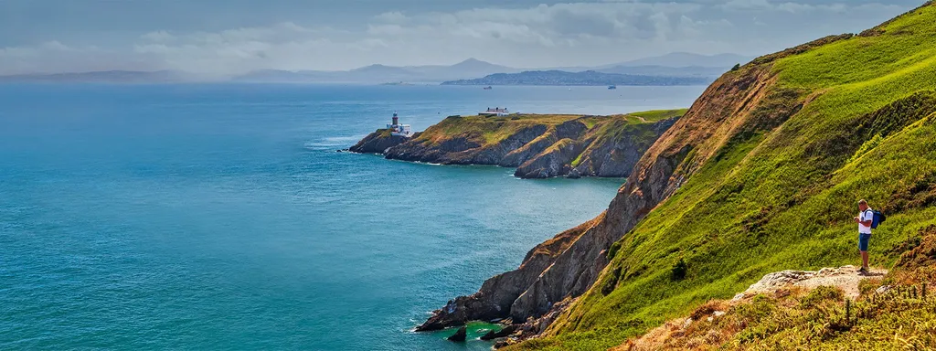 Green cliffs and a lighthouse on Howth Head above the sea